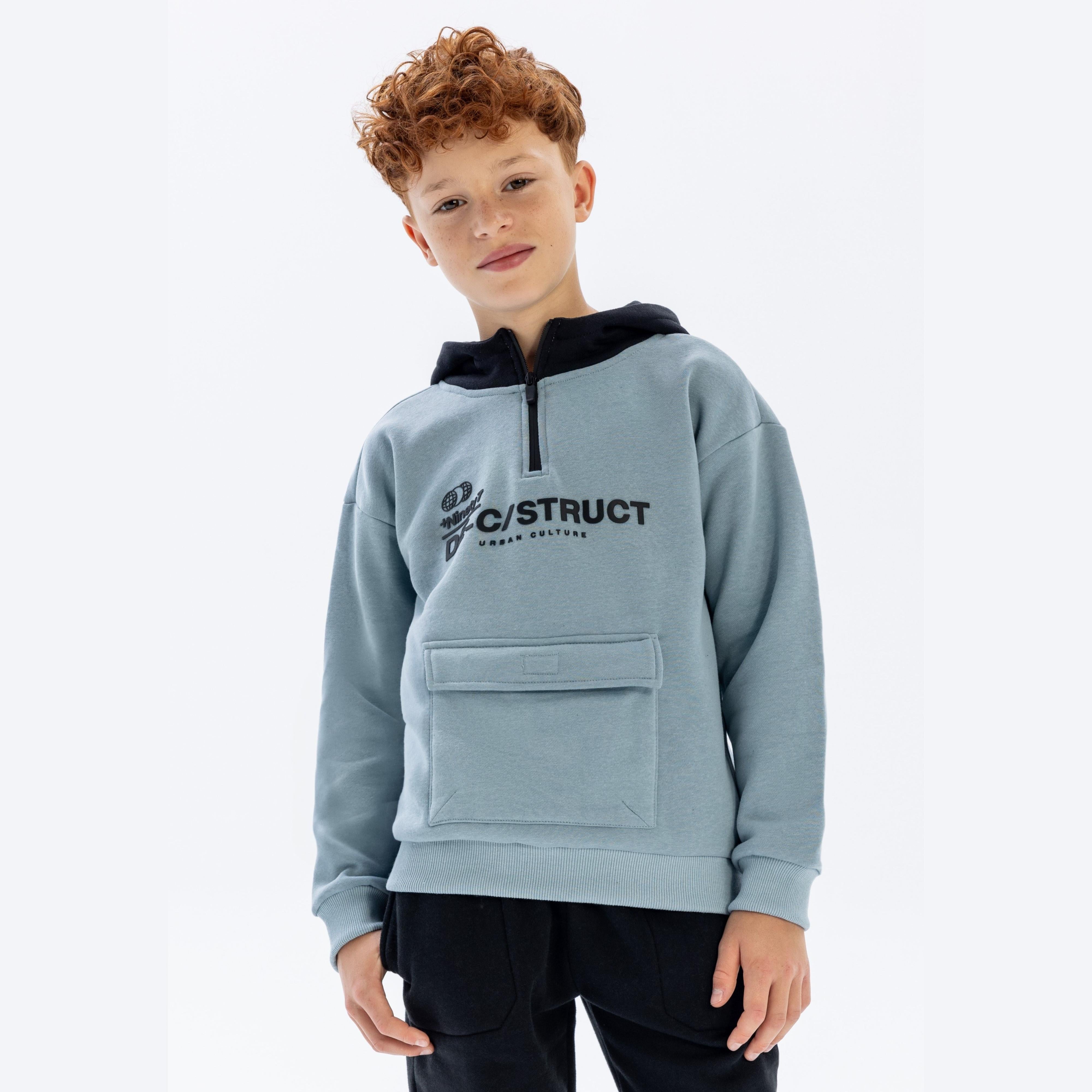 Boy wearing light blue half-zip hoodie with black hood and Deconstruct print, front view against white background