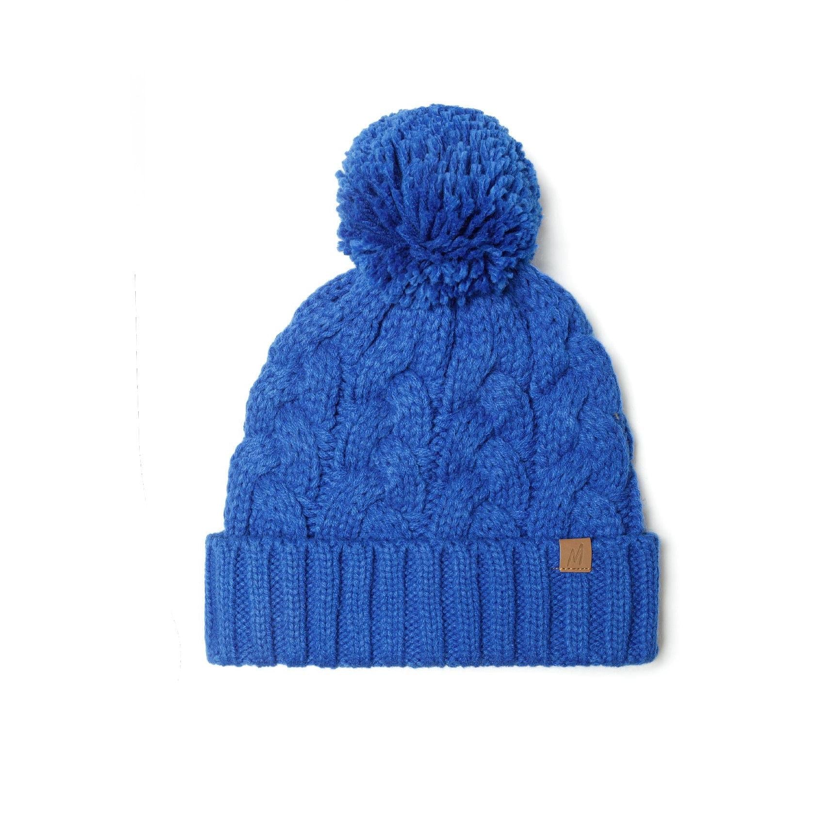 Cable knit beanie in cobalt blue with pom pom on white background, showing full front view with Minoti leather label