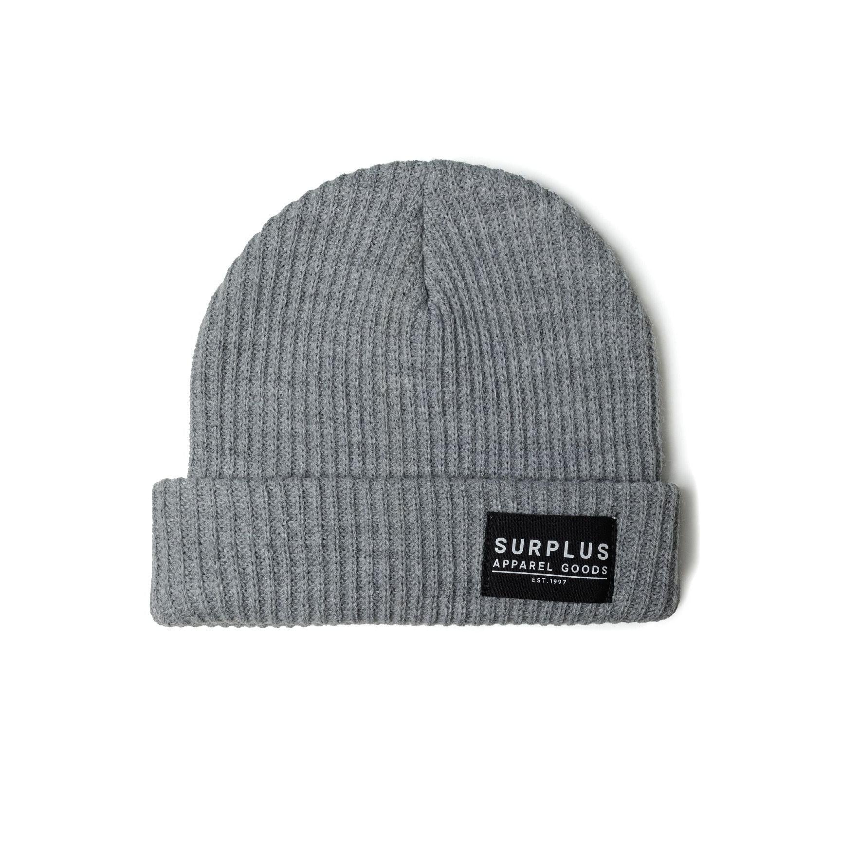 Close-up view of green ribbed knit beanie on white background showing texture and black woven label detail