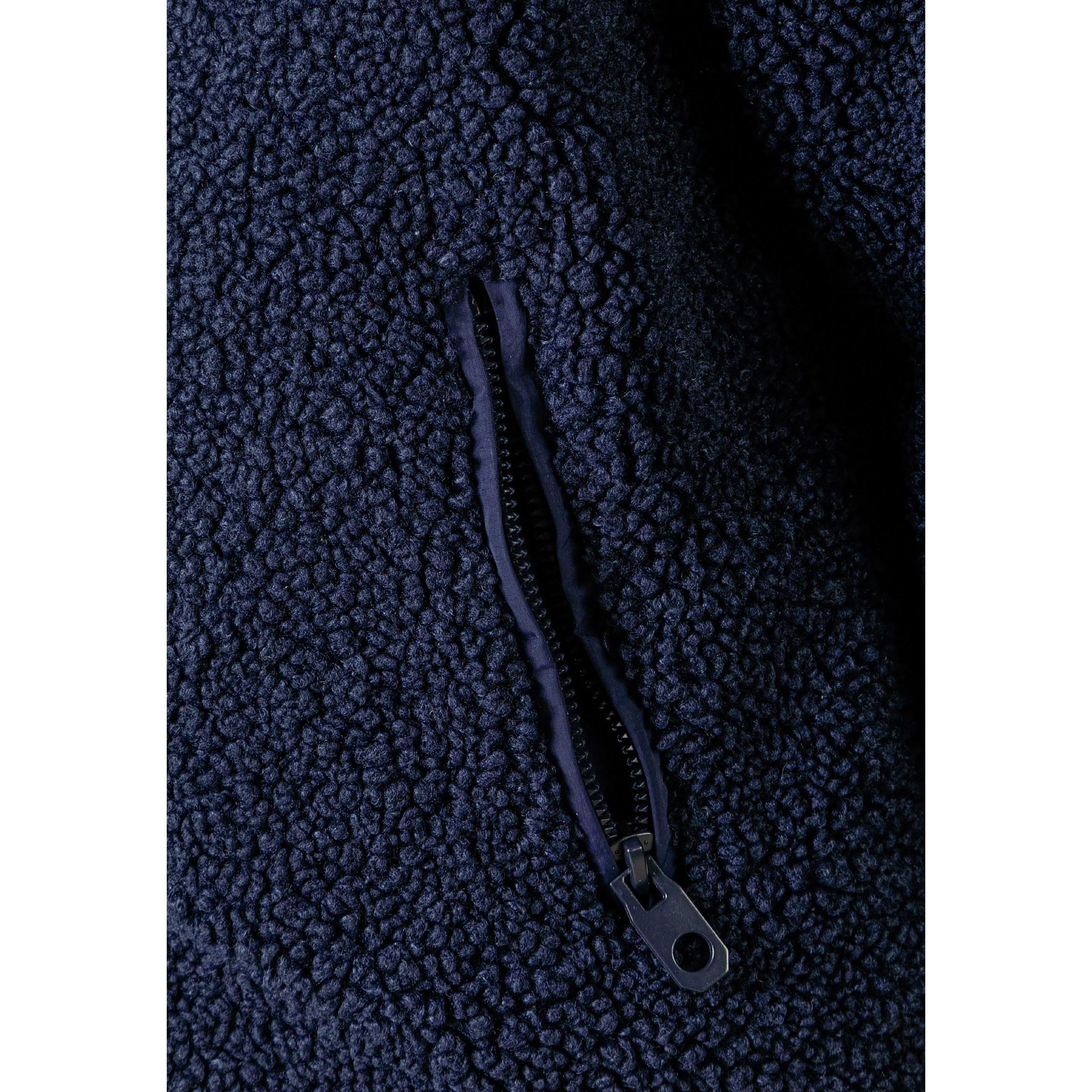 Close-up detail of navy borg jacket showing zip pocket with navy zipper pull on textured sherpa fabric