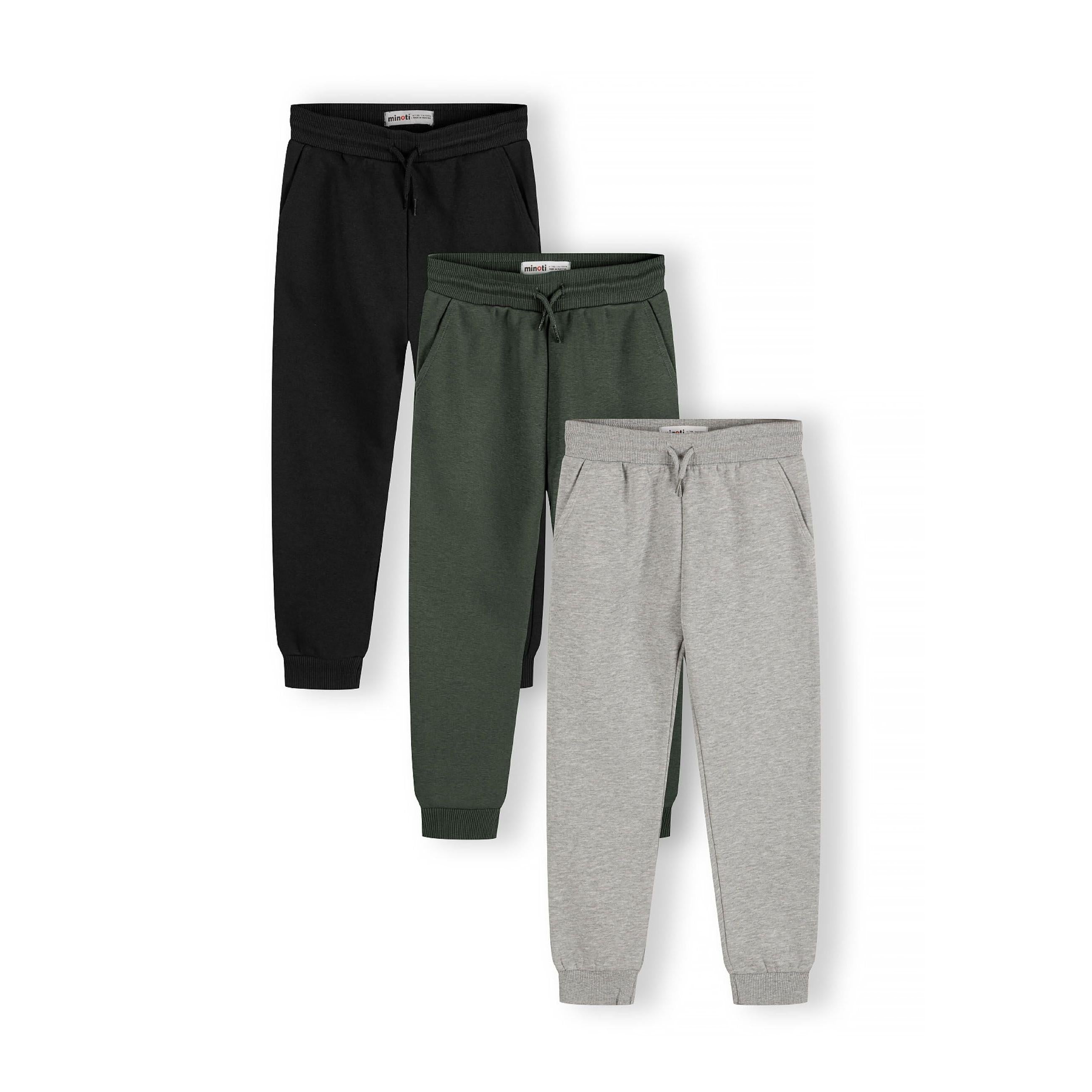 Three pairs of children's joggers displayed overlapping - black, green and grey sweat fabric joggers with ribbed ankle cuffs and drawstring waists against white background
