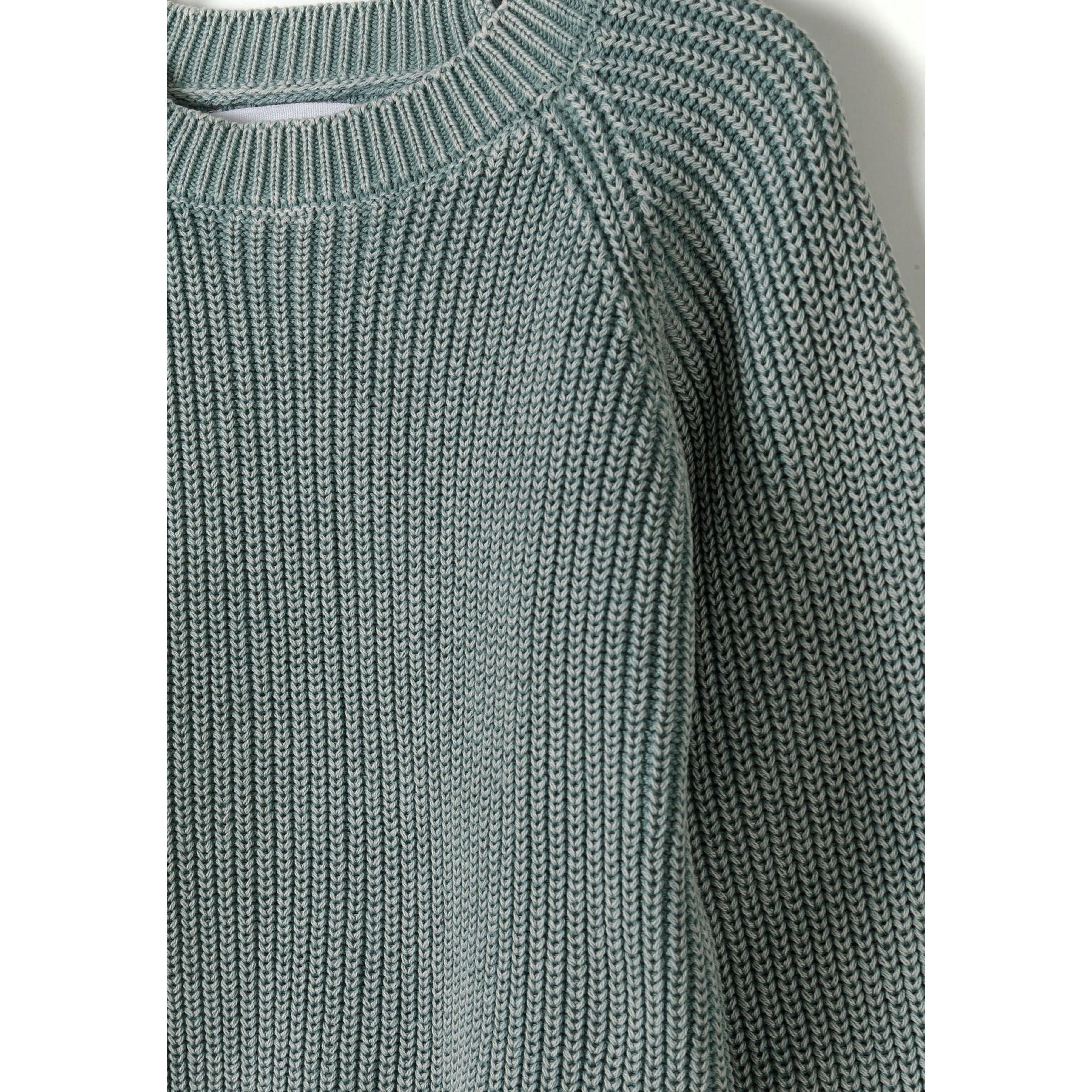 Close-up detail of khaki knit jumper showing ribbed texture and washed effect finish with crew neckline construction