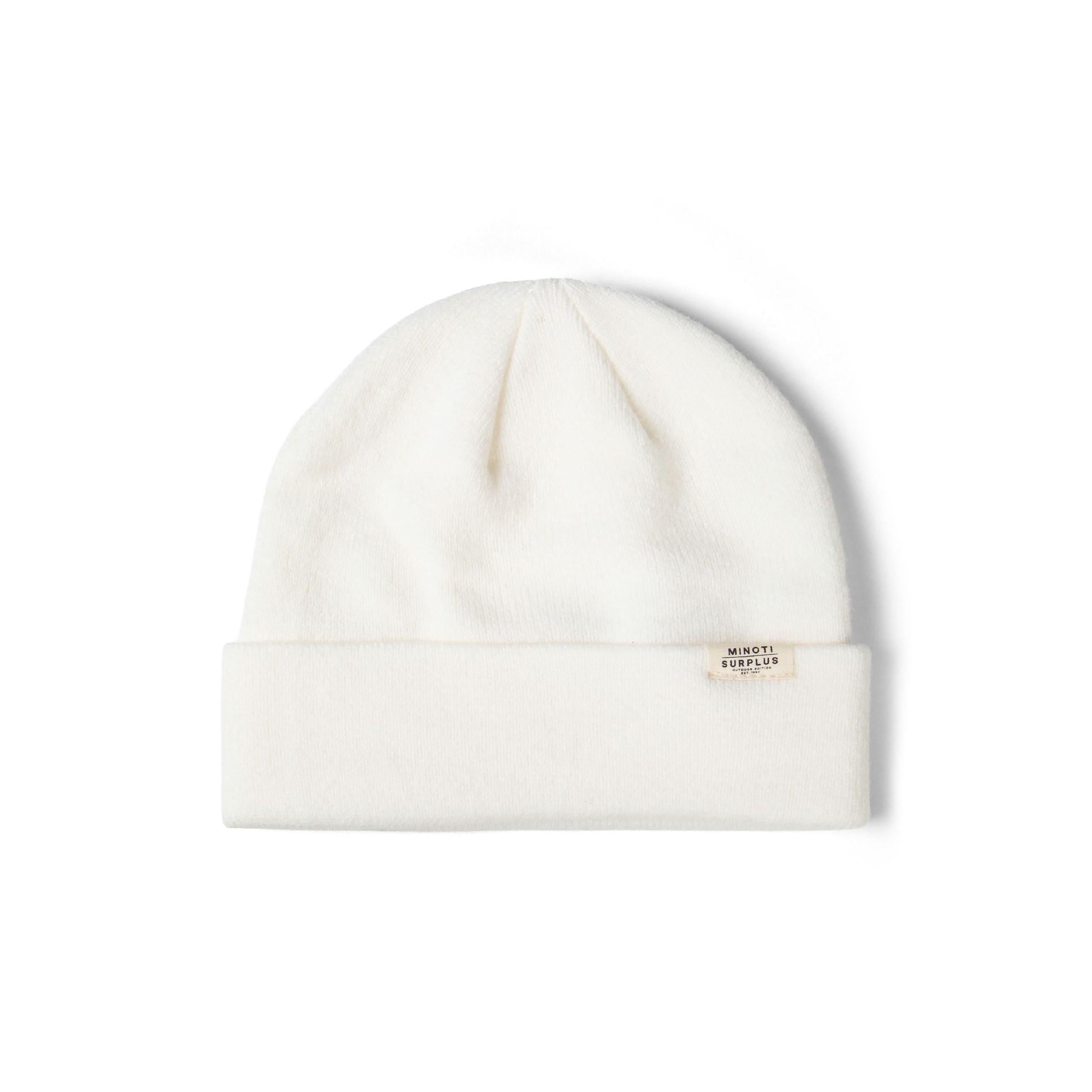 Flat lay of cream ribbed beanie with Minoti Surplus woven label on white background, showing classic knit construction