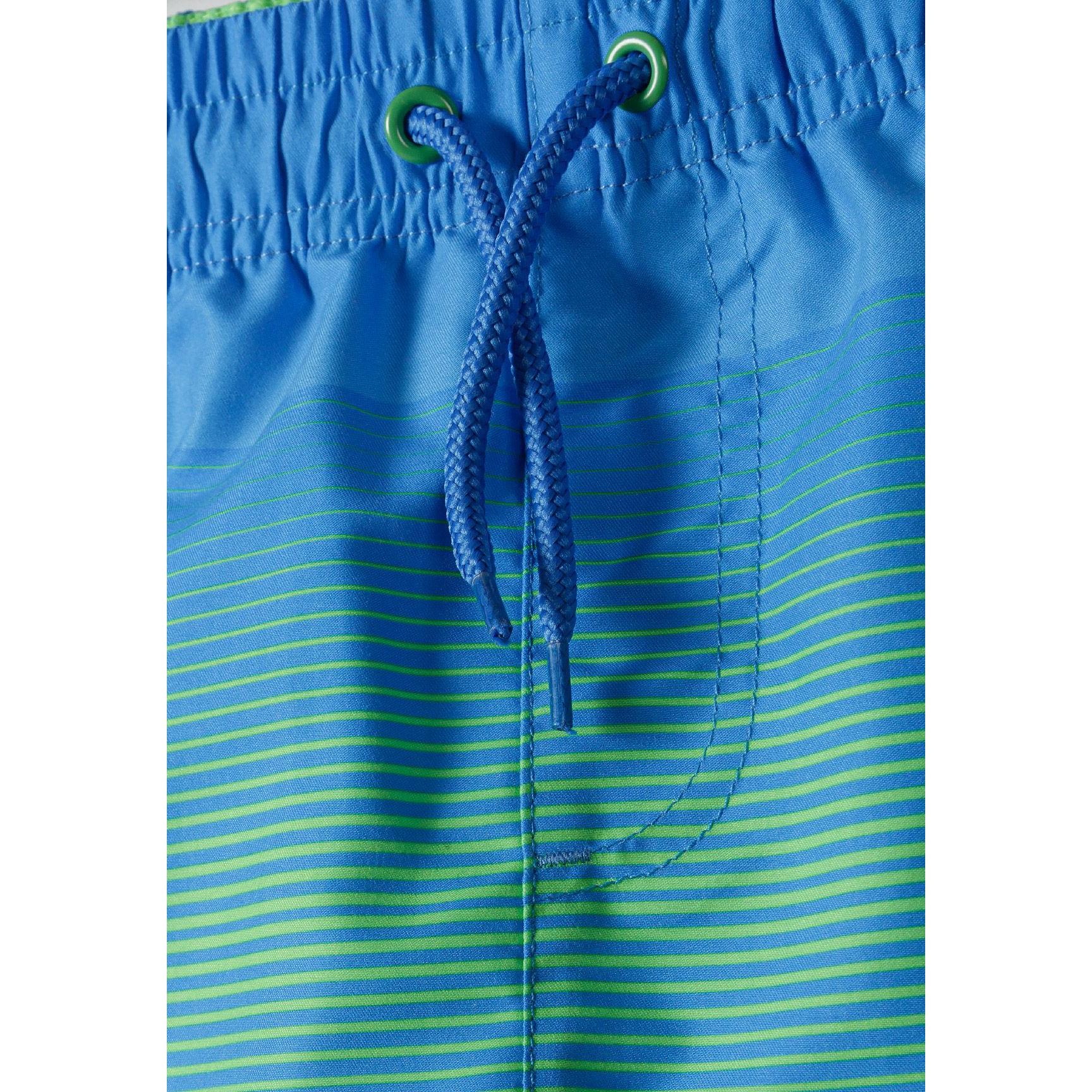 Close-up detail of waistband showing blue drawstring with green eyelets and striped gradient pattern