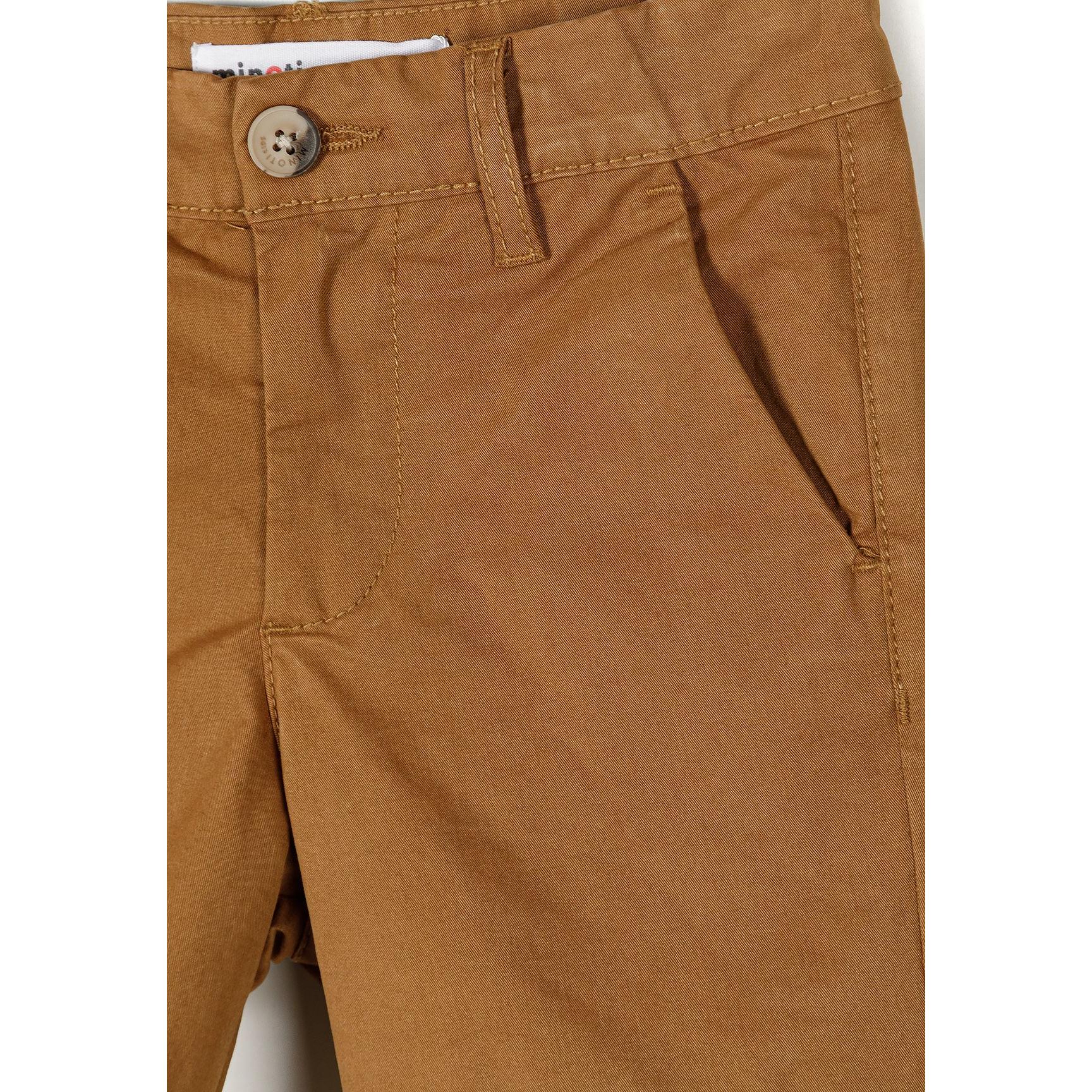 Detail view of sand chino shorts waistband area showing Minoti label, button closure, belt loops, and front pocket construction with visible topstitching