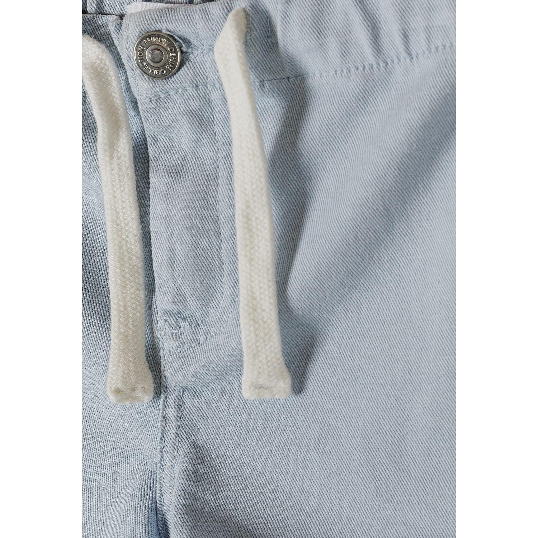 Detail shot of light blue twill shorts showing white cotton drawstring ties, metal button fastening, and fabric texture on white background