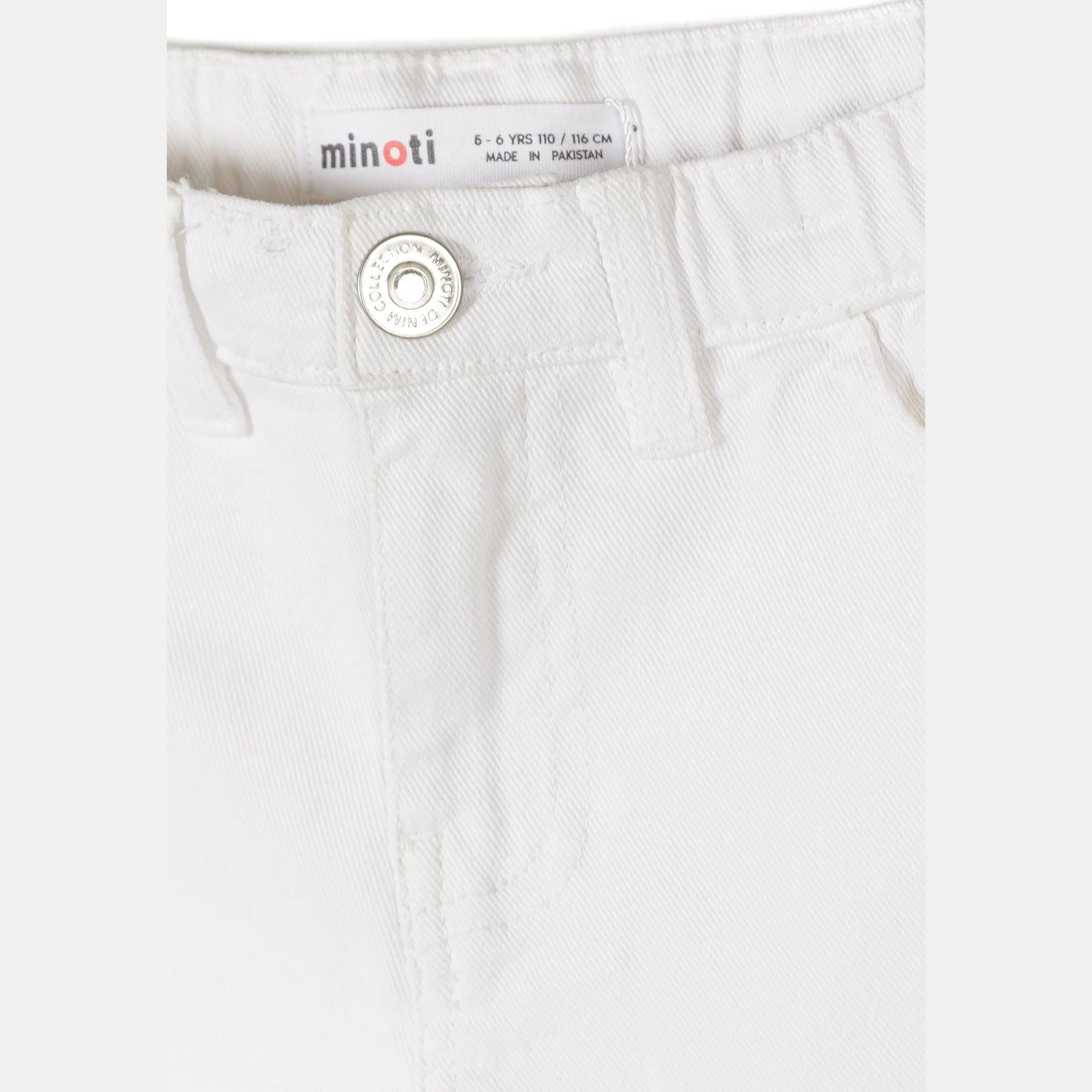 Close-up detail of white twill shorts showing Minoti brand label in waistband reading '6-7 YRS 110/116 CM MADE IN PAKISTAN' with button closure visible