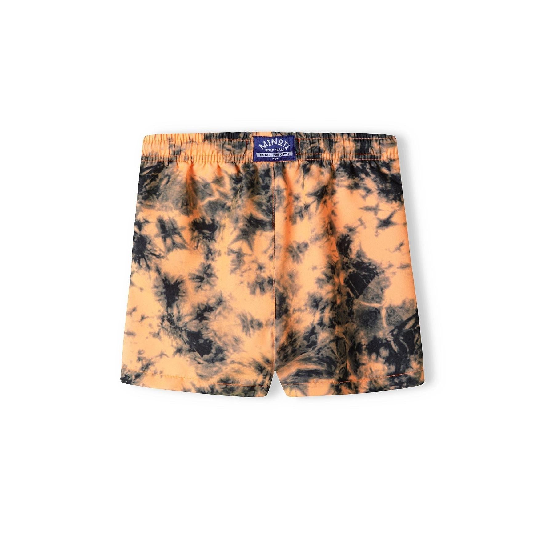 Back view of tie-dye board shorts showing Minoti label and continued pattern coverage across rear panel on white background