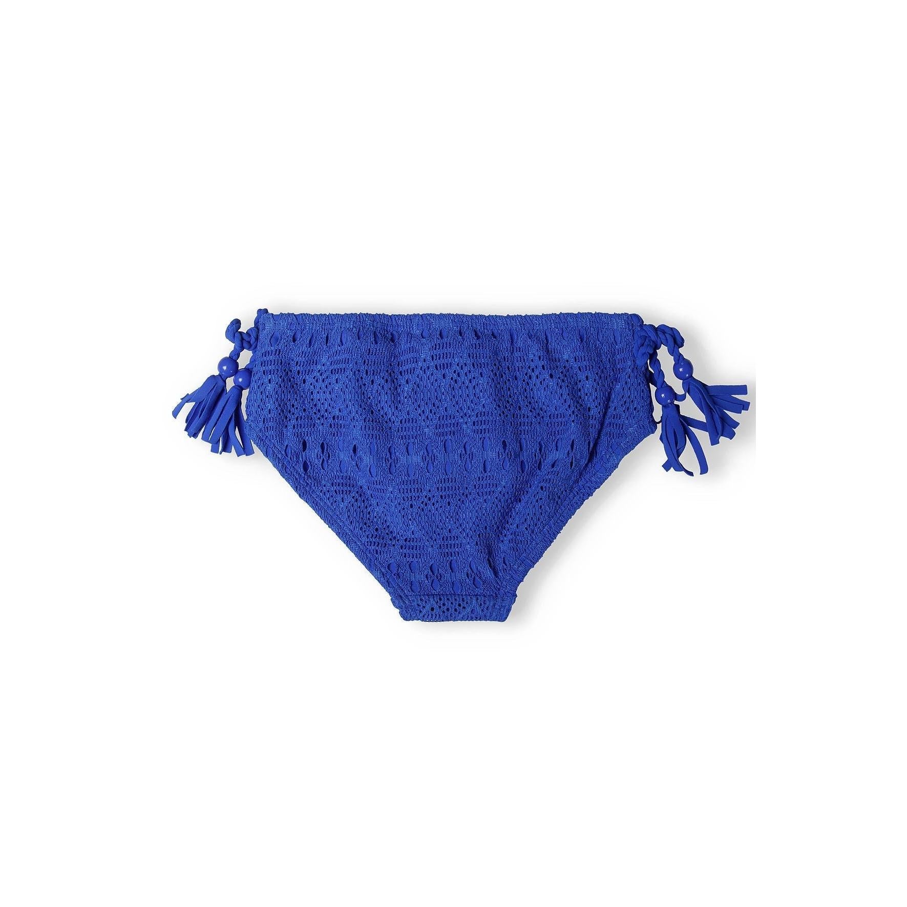 Close-up view of cobalt crochet bikini bottoms showing decorative side tassels and intricate textured fabric pattern on white background