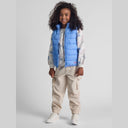 Smiling girl in light blue quilted gilet with full zip, worn over a white long-sleeve top and beige cargo pants.