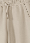 Close-up of girls beige wide leg joggers showing elasticated waistband and drawstring with pocket detail design.