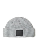 Detail of a grey knitted fisherman hat with a ribbed brim and logo badge.