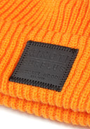 Detail of bright orange knitted fisherman hat with badge.