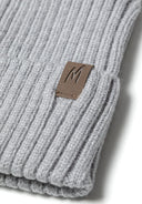Detail of a ribbed knit hat in gray with a tab detail on the cuff.