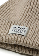 Detail of a khaki knitted rib hat with badge.