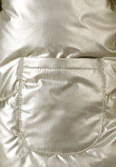 Detail of a girls metallic padded jacket in gold, featuring a pocket and shiny surface.
