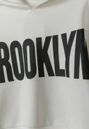 Close-up of a girls' white hooded sweatshirt featuring 'BROOKLYN' print.