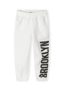 Close-up of white joggers with elasticated waistband and 'BROOKLYN' print on the side.