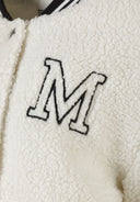 Detail of cream borg baseball jacket with embroidered 'M' on chest.