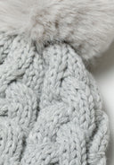 Detail of a grey knitted cable pom pom hat for girls, featuring a soft pom pom on top.