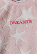 Close-up of a pink girls' pyjama top with star pattern and 'DREAMER' embroidery.