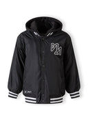 Boys baseball style jacket in black, front view with detachable hood and striped cuffs.