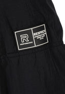 Detail of a black quilted jacket featuring a rubber logo patch.