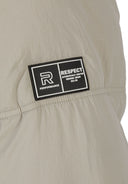 Detail of a boys quilted jacket with a rubber patch logo.