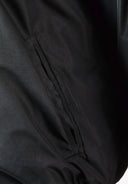 Detail of a black men's baseball jacket showing a side pocket.
