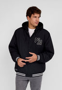 Men's black baseball jacket with detachable hood, ribbed cuffs, and embroidered detail.