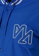 Close-up of a cobalt blue men's baseball jacket featuring a logo and drawstring hood.