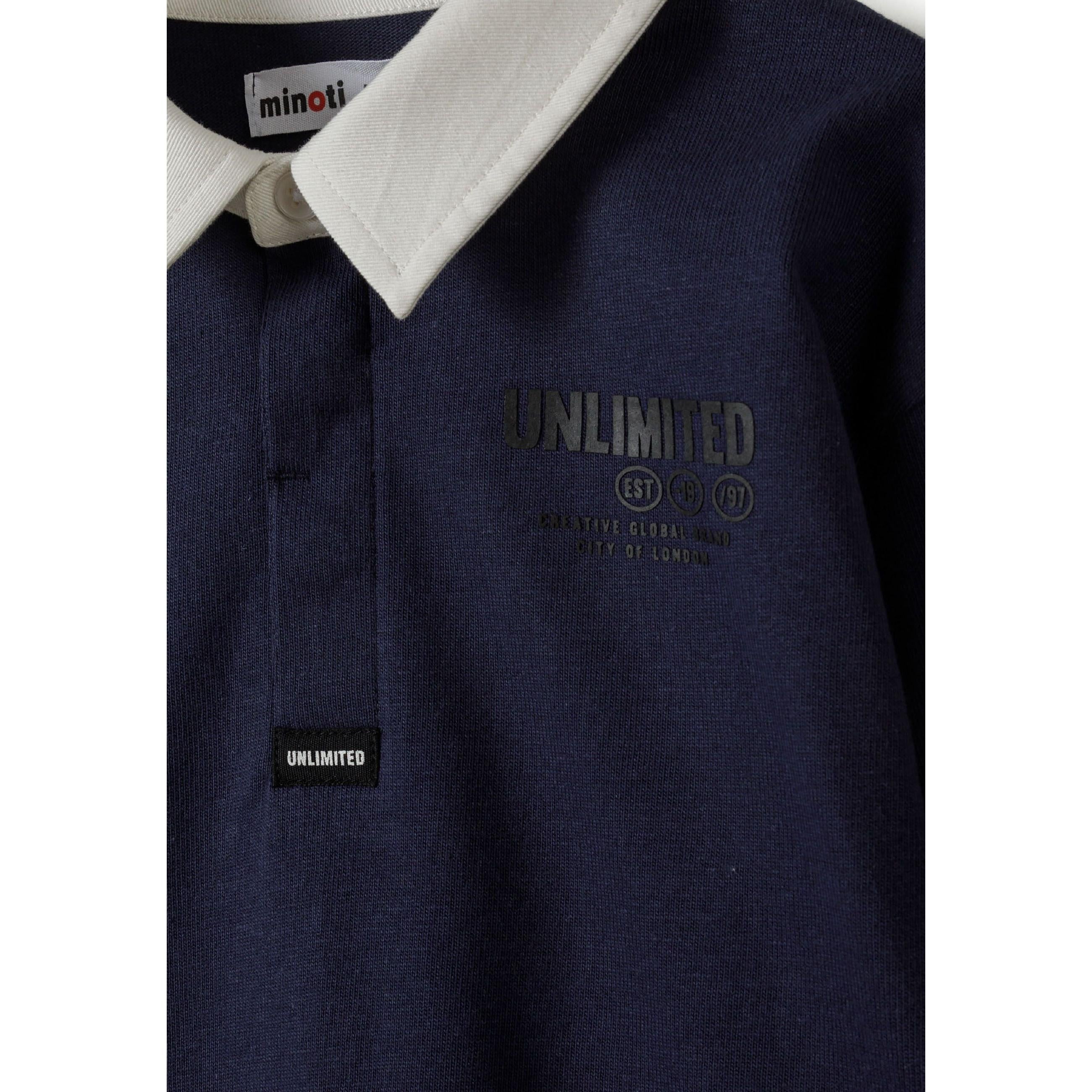 Close-up detail of navy polo shirt showing white collar, Minoti label and 'UNLIMITED' chest print with small logo tab