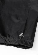 Detail of black waterproof overpants with logo and hem adjustment.
