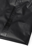 Detail of black waterproof overpants with visible stitching.