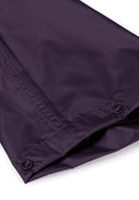 Detail of purple waterproof overpants with button closure and elasticated cuffs.