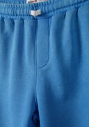 Detail of blue shorts with elasticated waistband and side pocket.