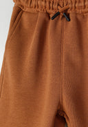 Close-up of beige shorts with elasticated waistband and side pockets.