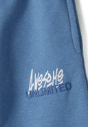 Detail of blue joggers featuring printed logo 'Awesome Unlimited'.