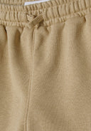 Detail of beige shorts with elastic waistband and drawstring.