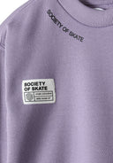 Detail of lilac oversized boys' crew neck sweatshirt with logo patch.