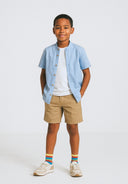 Boys grandad shirt in light blue with button fastening and beige shorts, front view.