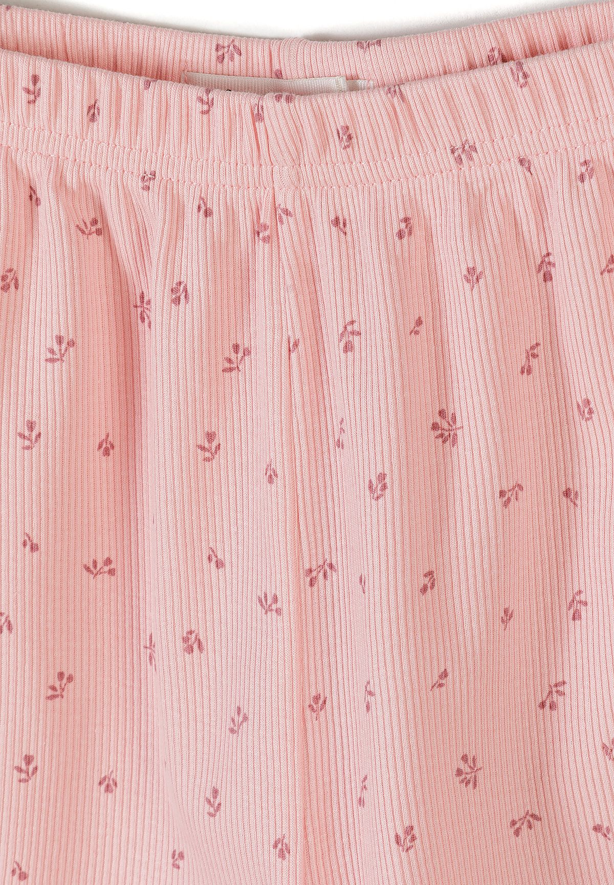 Detail view of pink ribbed fabric texture showing delicate floral print pattern and elastic waistband