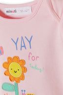 Close-up of a pink baby bodysuit with a colorful flower design and cheerful "YAY for today" text on soft fabric.