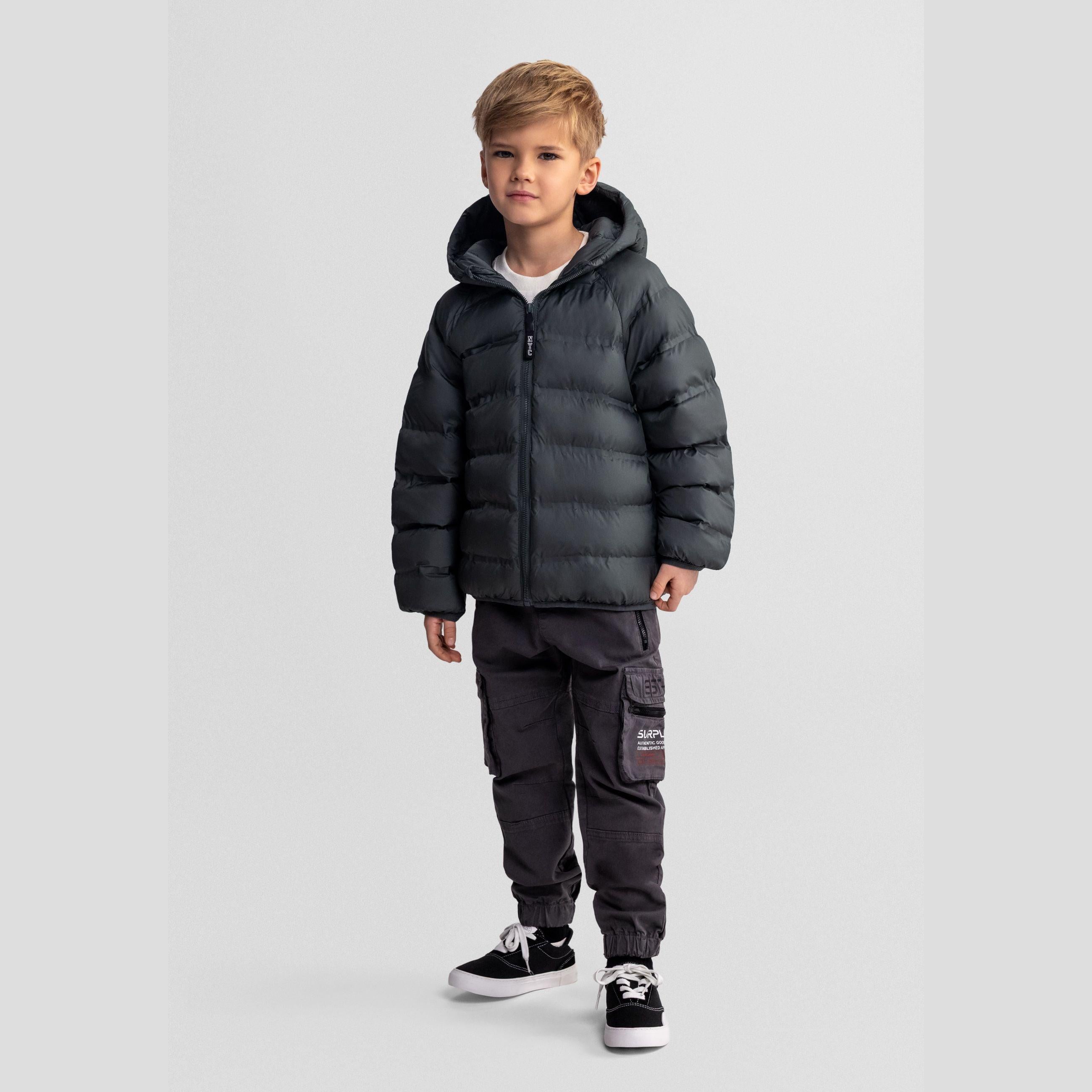 Young boy wearing emerald green padded jacket with hood and dark cargo pants, standing against white background