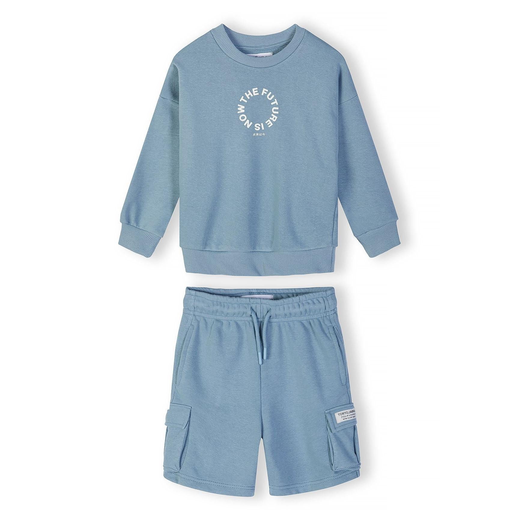 Back view of blue grey sweatshirt showing circular 'The Future is Now' text print with Japanese characters below