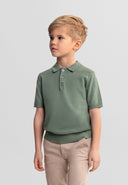 Young boy wearing a deep forest green knitted polo shirt with a classic collar and short sleeves, showing stylish design.