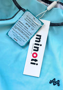 Close-up of turquoise rash vest fabric with black stitching and Minoti brand tag showing UV protection details.