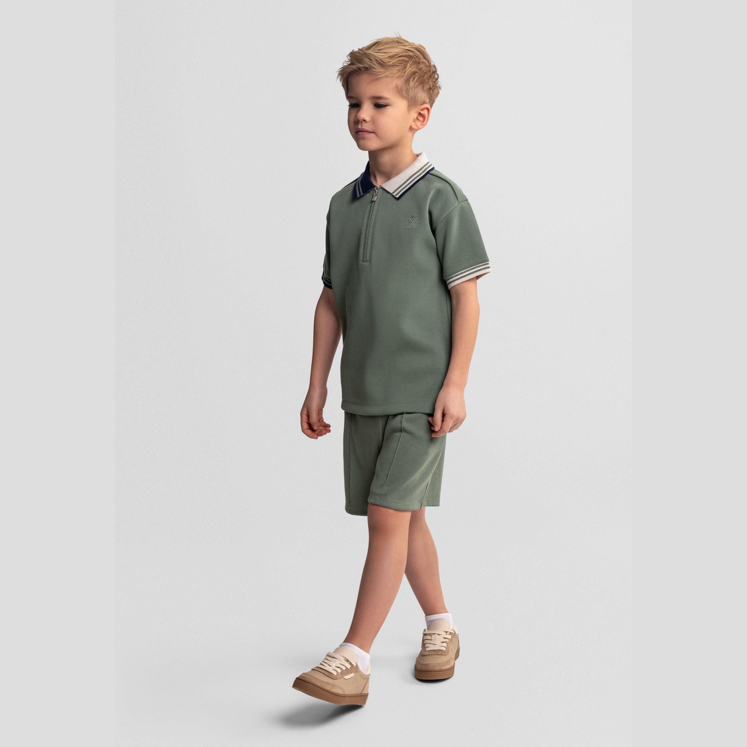 Flat lay of teal pique polo shirt with contrast collar trim and half-zip closure on white background