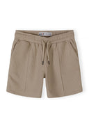 Detail of boys' shorts with elasticated waistband and side pockets in muted sand.