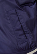 Detail of navy varsity bomber jacket showing side-seam pocket and elasticated cuff.